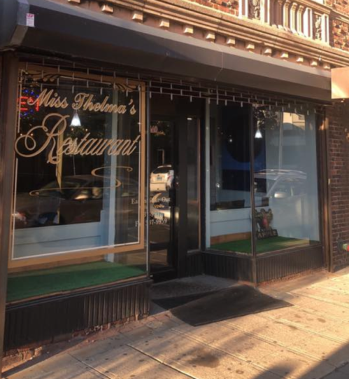 Exterior of Miss Thelma's Restaurant, featuring large windows and a welcoming entrance on a city street.