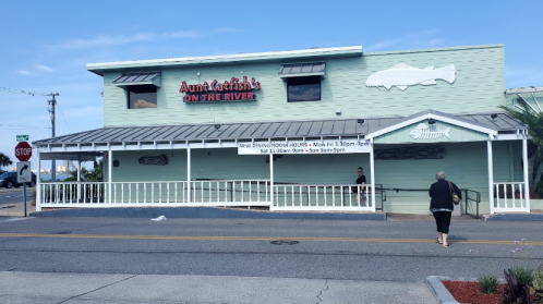 Exterior of Aunt Catfish's on the River restaurant, featuring a light green building and a sign above the entrance.