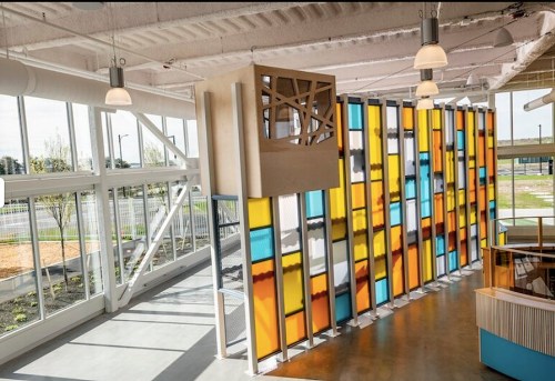 Brightly colored glass panels in a modern interior space with large windows and a wooden structure above.