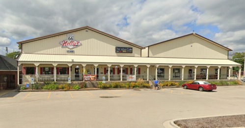 A large, beige building with a sign reading "Route 66 Lettuce," featuring a porch and parked cars in front.