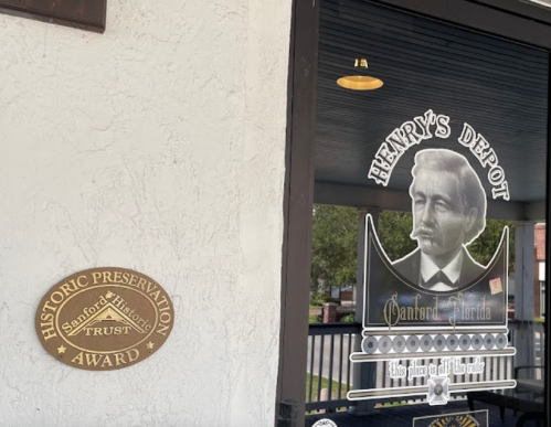 Sign for Henry's Depot featuring a portrait and a historic preservation award plaque on the wall.