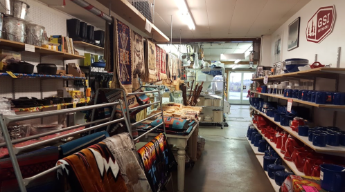A cozy store aisle filled with colorful textiles, pottery, and various home goods, showcasing a vibrant shopping atmosphere.