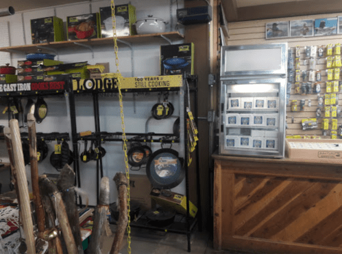 A store interior featuring shelves of cookware, fishing gear, and a display case with various items.