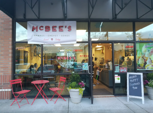 Exterior of McBee's, a shop with a sign for shakes, crepes, and cones, featuring red chairs and a welcoming entrance.