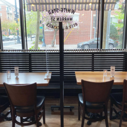 Interior of a restaurant with wooden tables and chairs, featuring a large window and a sign for "White Star."