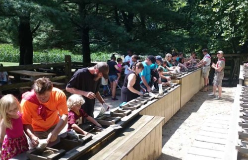 A group of people, including children, are engaged in a gem mining activity at an outdoor venue.