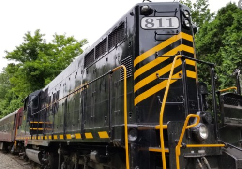 A black and yellow train engine with the number 811, parked among green trees.