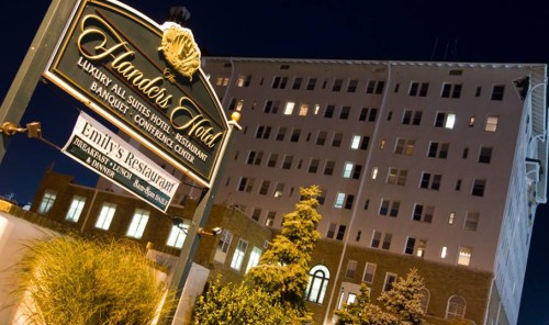 Sign for Handers Hotel and Emily's Restaurant, with a multi-story building in the background, illuminated at night.