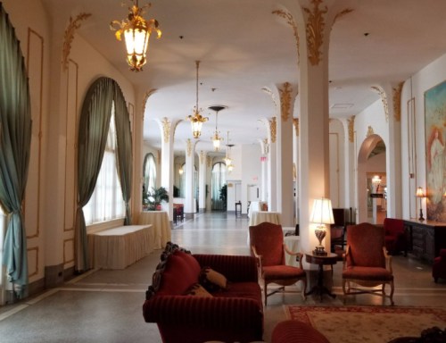 Elegant hotel lobby featuring ornate decor, plush seating, and large windows with soft lighting.