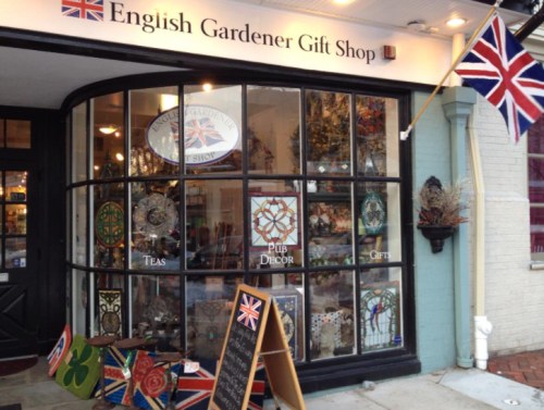 A charming gift shop with large windows displaying decorative items, teas, and gifts, featuring a British flag.