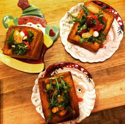 Three plates with crispy fried squares topped with arugula, cherry tomatoes, and mozzarella, festive holiday designs.