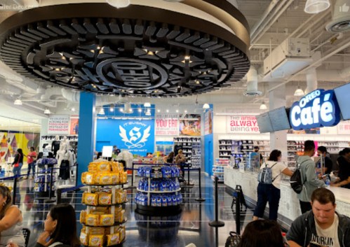 A vibrant store interior featuring a snack display, a café area, and customers browsing in a modern setting.