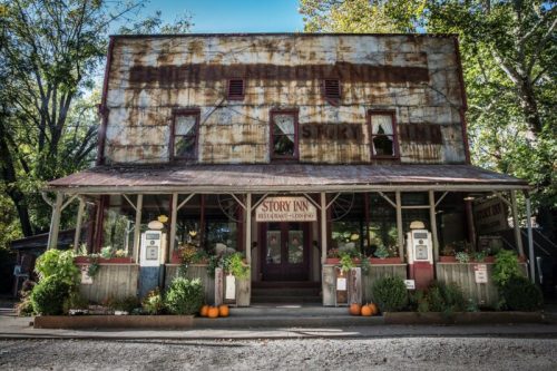 Historic building with a rustic facade, featuring the "Story Inn" sign, surrounded by greenery and pumpkins.