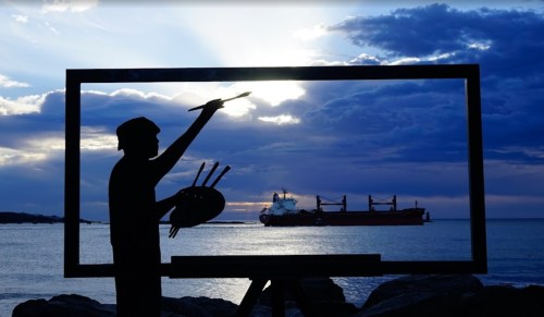 A silhouette of a painter with a palette, framed by an easel, against a backdrop of a ship and a dramatic sky.