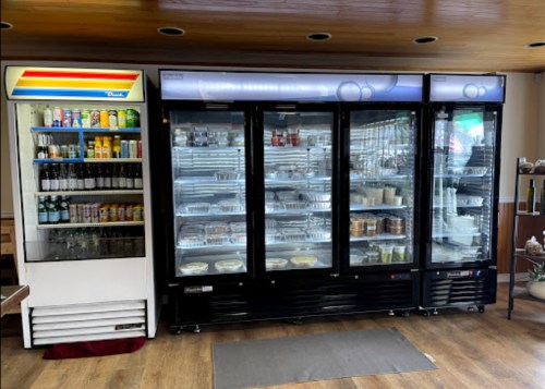 A display of two refrigerators: one with drinks and snacks, the other with various prepared food items.