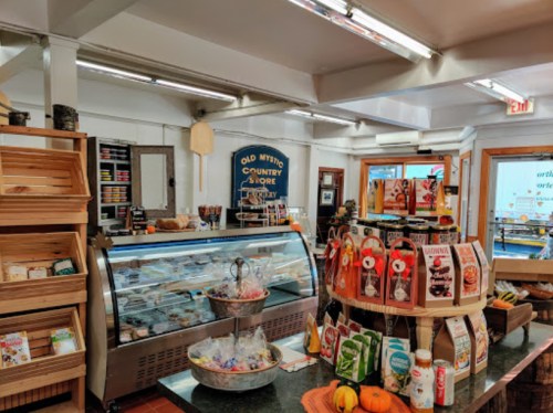 A cozy country store interior featuring a display case, shelves of goods, and seasonal decorations.