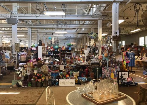 A spacious antique store filled with various vintage items, furniture, and decor arranged on shelves and tables.