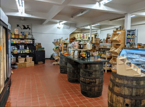 A cozy store interior with wooden shelves, barrels, and various packaged goods displayed throughout the space.