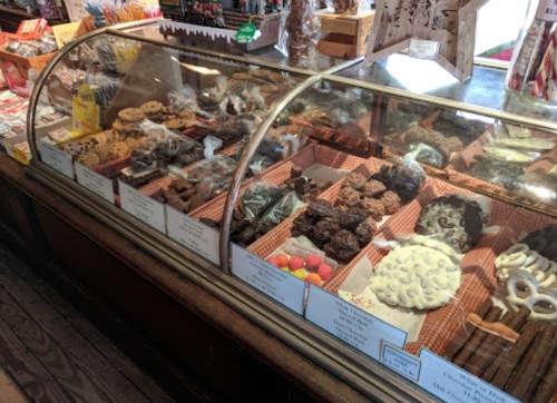 A display case filled with various cookies and candies, showcasing an assortment of treats in a cozy shop.