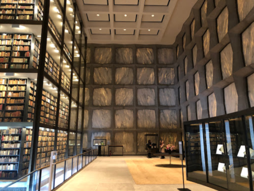 Modern library interior featuring tall bookshelves, textured walls, and a spacious, well-lit reading area.