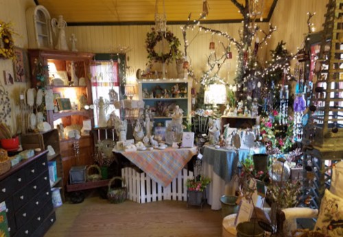 A cozy shop filled with decorative items, figurines, and plants, illuminated by warm lights and a welcoming atmosphere.