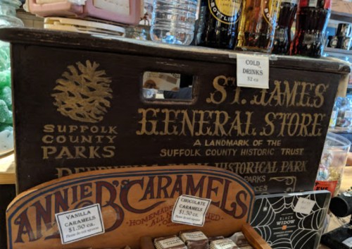 A wooden display box at a general store featuring signs for drinks and various caramel treats.