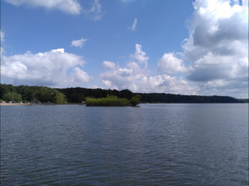A serene lake scene with an island of greenery under a partly cloudy sky.