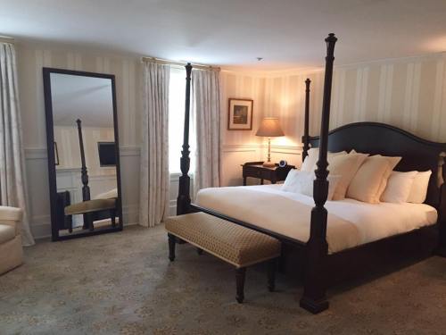 A cozy hotel room featuring a four-poster bed, a large mirror, and soft lighting with elegant decor.