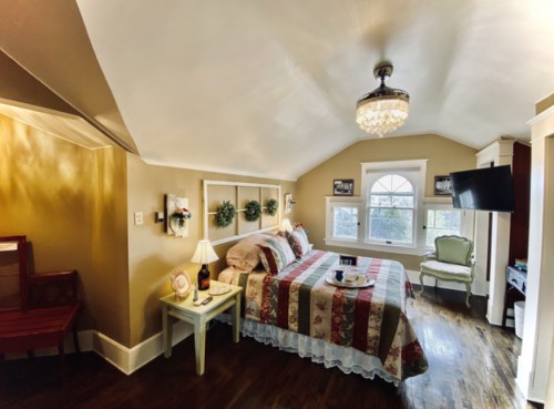 Cozy bedroom with a striped bedspread, elegant lighting, and a window offering natural light.