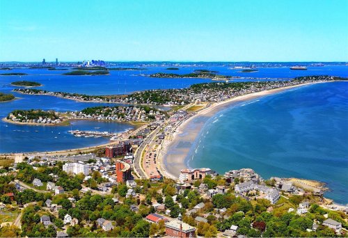 Aerial view of a coastal landscape featuring sandy beaches, islands, and a city skyline in the distance.