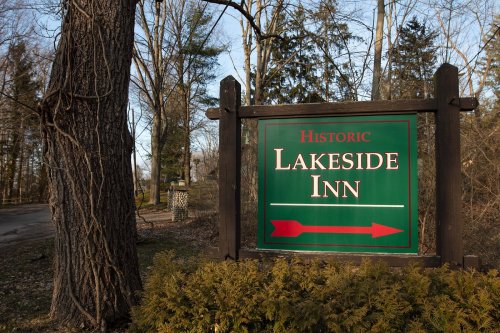 Sign for Historic Lakeside Inn with an arrow pointing right, surrounded by trees and greenery.