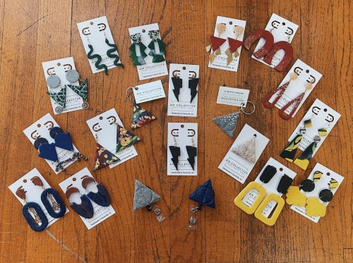 A variety of colorful earrings displayed on cards, arranged on a wooden surface.