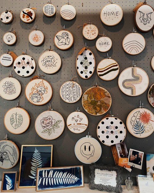 A wall display of various embroidered hoop art featuring designs, words, and patterns in a creative arrangement.