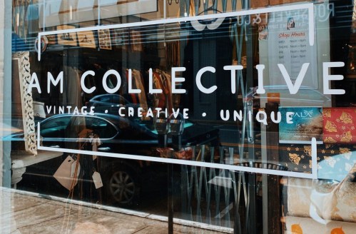 A storefront window displaying the sign "AM COLLECTIVE" with the words "Vintage • Creative • Unique."