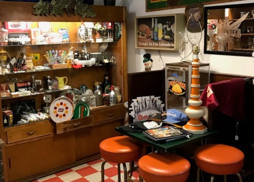 A cozy vintage display with a wooden cabinet, colorful decor, and retro stools in a nostalgic setting.