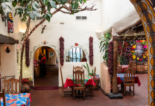 Colorful restaurant interior with vibrant tablecloths, decorative plants, and traditional Mexican decor.