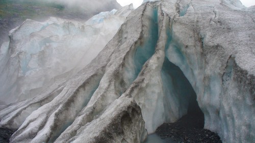 A close-up of a glacier with textured ice formations and a misty background.
