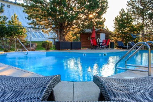 A serene pool area with lounge chairs, surrounded by trees and a cozy shed, illuminated by warm sunset light.