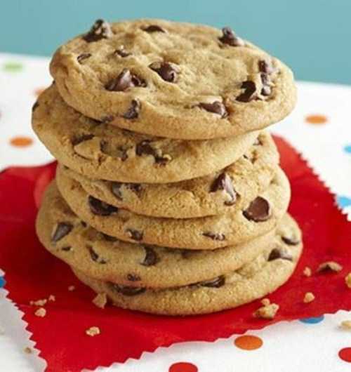 A stack of chocolate chip cookies on a red napkin, surrounded by colorful confetti.