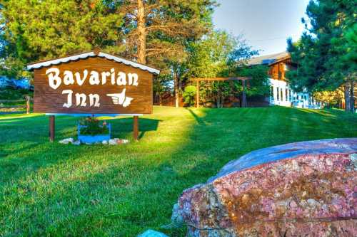 Sign for Bavarian Inn in a grassy area, surrounded by trees and a building in the background.