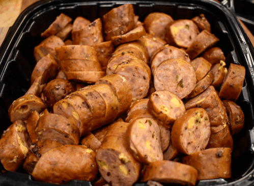 A close-up of sliced sausage pieces arranged in a black container.