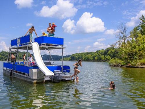 A group of people enjoying a sunny day on a pontoon boat with a slide, swimming and playing in the water.