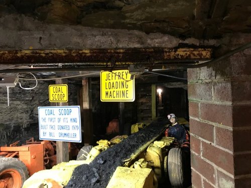 Underground mining scene with coal loading machinery and informational signs about coal scoop and Jeffrey loading machine.
