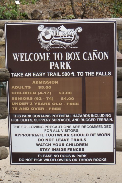 Sign at Box Canyon Park detailing admission prices and safety precautions for visitors.