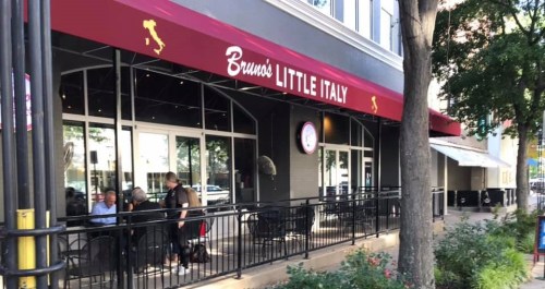 Exterior of Bruno's Little Italy restaurant, featuring outdoor seating and a red awning in a city setting.