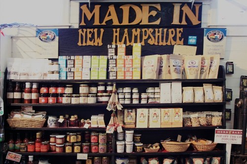 A display shelf featuring various products labeled "Made in New Hampshire," including jars, snacks, and packaged goods.