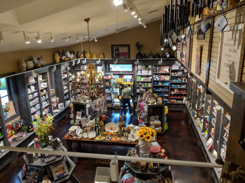 A cozy gift shop filled with colorful merchandise, shelves lined with products, and a customer browsing in the center.