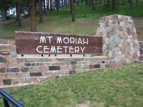 Sign for Mt. Moriah Cemetery, set against a backdrop of trees and stonework.