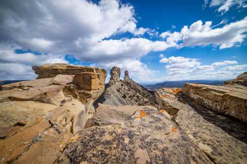 Rocky landscape with towering formations under a blue sky filled with clouds.