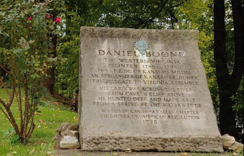 A stone monument honoring Daniel Boone, detailing his contributions as a pioneer and militia leader in West Virginia.